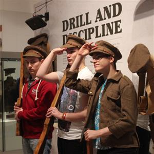 Three young men try on old army uniforms in a museum