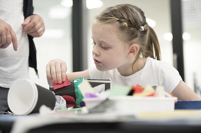 A girl creating a model car from recyclables