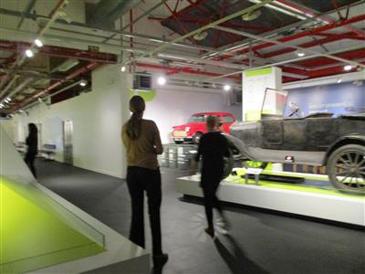 a group of people looking at vehicles in the museum
