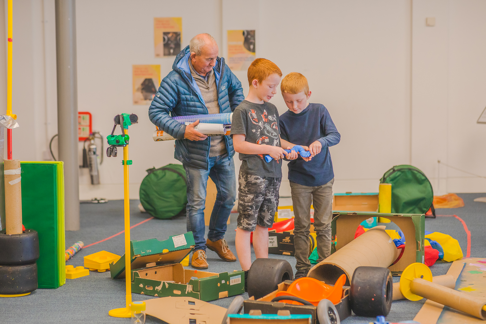 Two boys and a man building a car out of a range of objects at Coventry Transport Museum