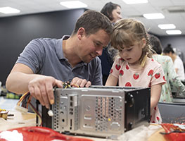 A man and a little girl taking apart an electronic appliance