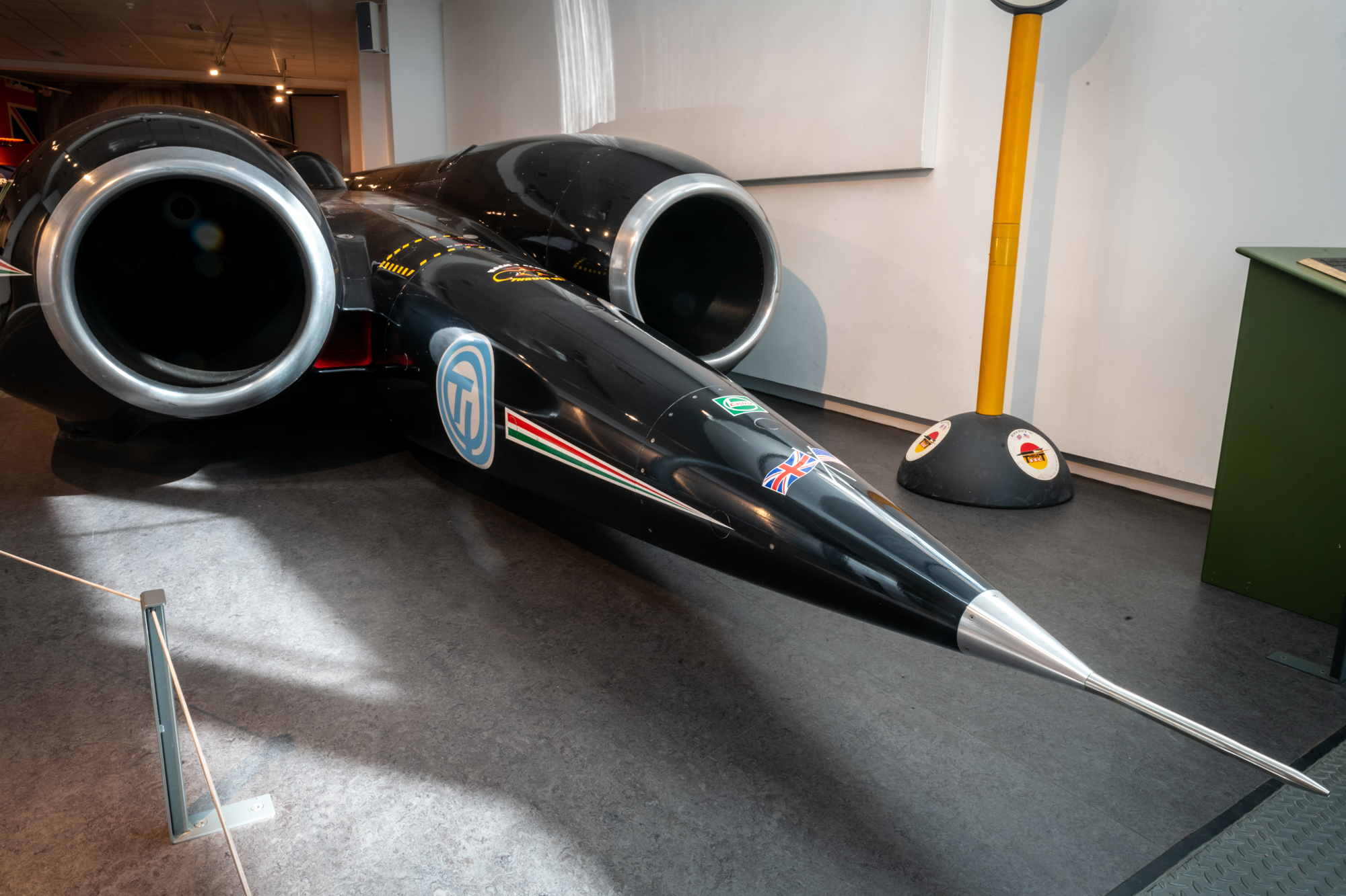 Side view of Thrust SSC on display in Coventry Transport Museum, showing the full length of the car's nose