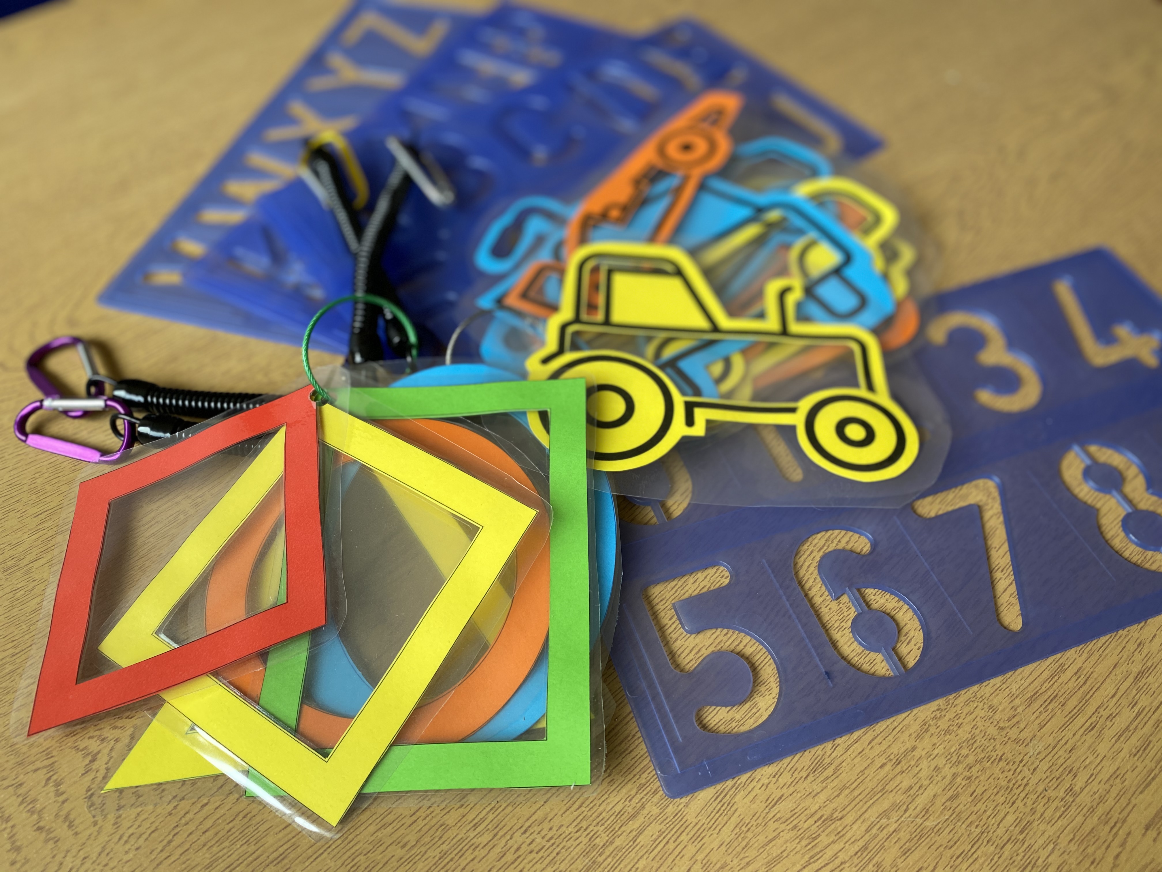 A selection of play items including number and alphabet stencils and cut-out, laminated tractors and squares