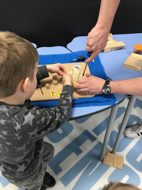 a young boy using string to wind around nails in a board