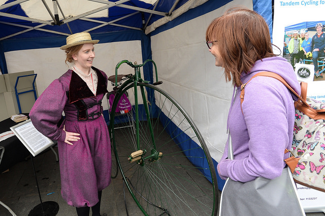 woman in period costume with penny farthing