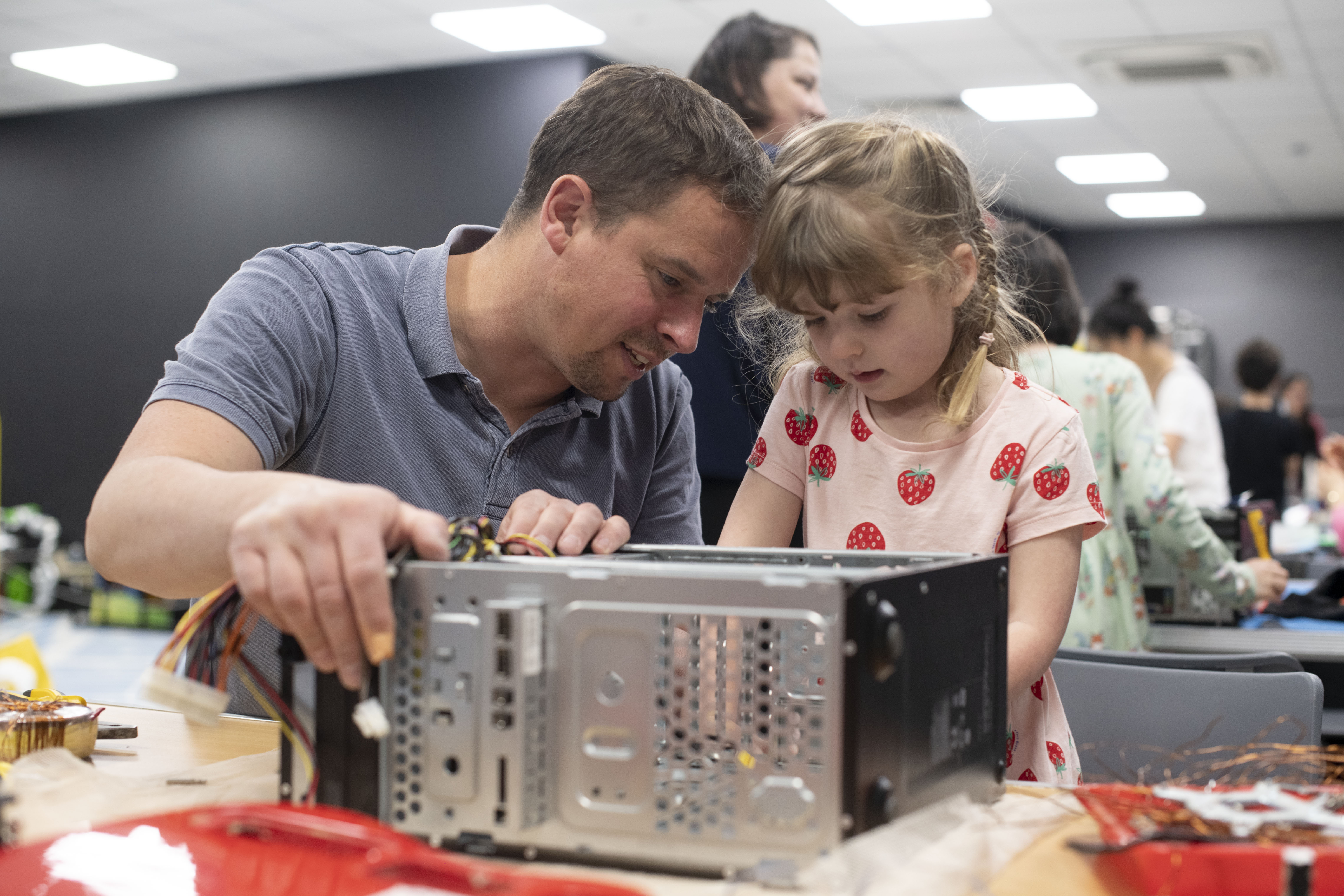 A man and a little girl working together to take apart an old computer